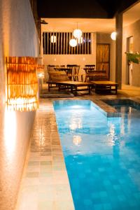 ein Swimmingpool in einem Hotel mit Tischen und Stühlen in der Unterkunft Vila Malie milagres in São Miguel dos Milagres