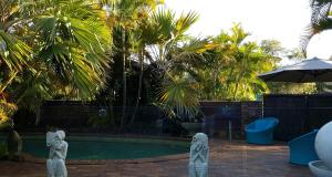 a swimming pool with statues and an umbrella at Ballina Palms Boutique Motel in Ballina +31 photos