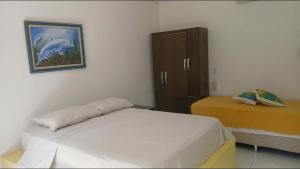 a bedroom with a bed and a cabinet with a painting at Suíte Santo in Santa Cruz Cabrália