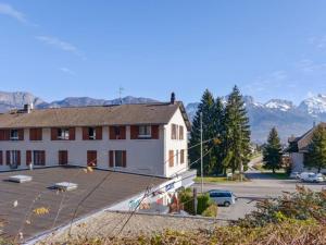 a building in a parking lot with mountains in the background at Entre lac et montagne 2 in Sévrier