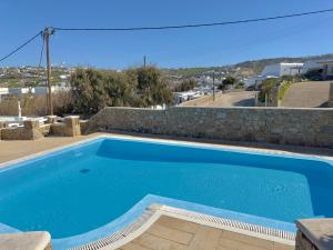ein großer blauer Pool neben einer Steinmauer in der Unterkunft Grace Villa Mykonos in Mykonos Stadt