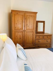 a bedroom with a bed with a dresser and a mirror at Sea Breeze Cottage on the North Wales Coast in Penrhyn Bay