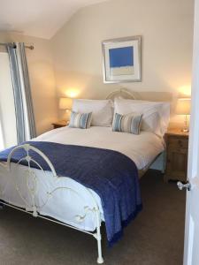 a bedroom with a white bed with a blue blanket at Sea Breeze Cottage on the North Wales Coast in Penrhyn Bay