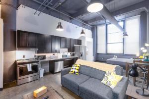 a living room with a couch and a kitchen at Heart of Strip District - King Bd - Rooftop and Gym in Pittsburgh
