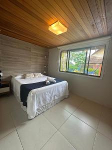 a bedroom with a large bed with a window at Bangalo Luxo Praia dos Carneiros Beach Resort in Praia dos Carneiros