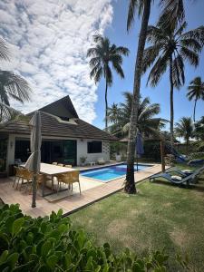 a backyard with a table and chairs and a swimming pool at Bangalo Luxo Praia dos Carneiros Beach Resort in Praia dos Carneiros