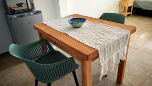 una mesa de madera con 2 sillas verdes y un tazón. en A18-Tu Ventana al Lago, en San Carlos de Bariloche