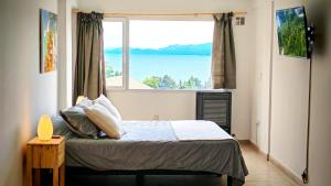 Un dormitorio con una cama con una ventana grande. en A18-Tu Ventana al Lago, en San Carlos de Bariloche