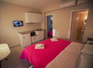 a bedroom with a red bed with two towels on it at Sunshine Resort in Lassi