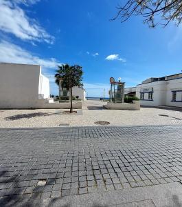 a cobblestone parking lot with a tree and a building at Casa Maria T1 in Armação de Pêra