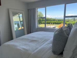 a white bed in a bedroom with a large window at Wineries and cycle tracks on your doorstep in Havelock North