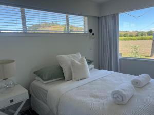 a bedroom with a white bed with towels on it at Wineries and cycle tracks on your doorstep in Havelock North