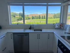 a kitchen with a sink and a large window at Wineries and cycle tracks on your doorstep in Havelock North +6 photos