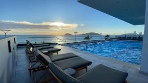 a swimming pool with chairs and a view of the ocean at Malecón Love in Mazatlán