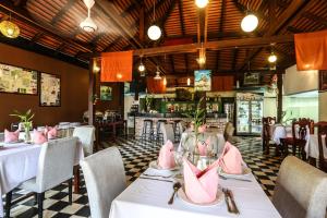 un restaurante con mesas y sillas blancas y un bar en Central Night Hotel, en Siem Reap