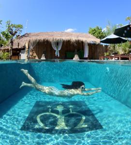 a woman laying in a swimming pool in a resort at Mans Cottages & Spa in Pemuteran