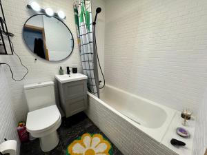 een badkamer met een bad, een toilet en een spiegel bij Bright & Cozy Central Studio in Reykjavík +9 foto's