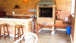 een buitenkeuken met een bakstenen oven en krukken bij Chacara Casa de Campo in Tietê