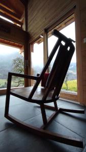 a rocking chair in a room with a window at Chalet savoyard écoresponsable, quasiment neuf 8 pers in Glières-Val-de-Borne