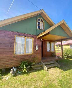 a green and wooden house with a porch at Cabaña en Contao Carretera Austral Hualaihué in Contao