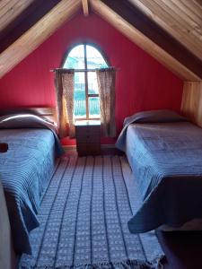 a red room with two beds and a window at Cabaña en Contao Carretera Austral Hualaihué in Contao