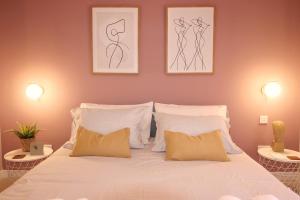 a bedroom with a white bed with two pictures on the wall at XV Studio Apartments - Rabat, Malta in Rabat
