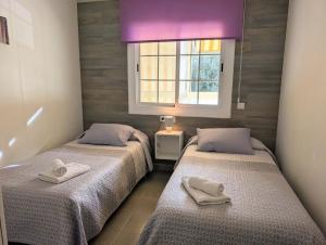 two beds in a room with a window at Apartamento Martin in Tossa de Mar