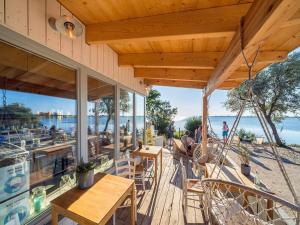 a porch with tables and chairs and a view of the water at Ferienwohnung in Lemkenhafen for 2 Personen in Lemkenhafen auf Fehmarn