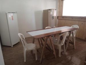a wooden table and chairs in a room with a refrigerator at Pousada in São Gabriel