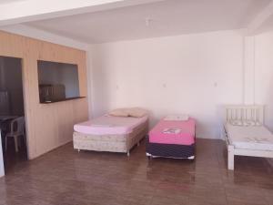 a room with two beds and a flat screen tv at Pousada in São Gabriel