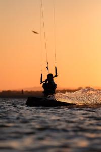 a person is windsurfing on the water at sunset at El Paraíso de Isla Canela in Isla Canela