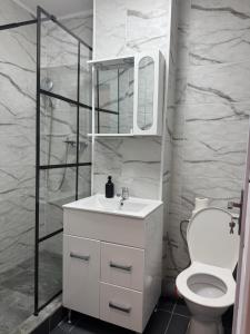 a white bathroom with a toilet and a sink at Best Rent Apartments in Giurgiu