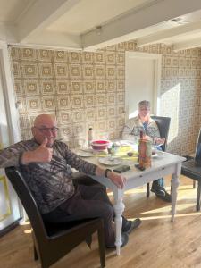two men sitting at a table in a room at Fiskesenter Birkeland Guesthouse in Vestnes