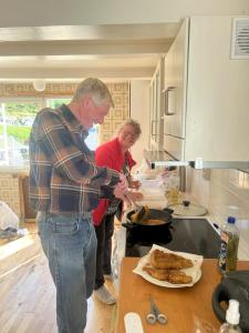 two people standing in a kitchen preparing food at Fiskesenter Birkeland Guesthouse in Vestnes