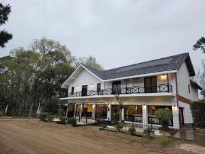 een groot wit gebouw met een balkon aan een onverharde weg bij Alamos Hosteria in Mar Azul