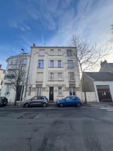 due auto parcheggiate davanti a un edificio di Le petit Lyautey - Retro-chic atmosphere a Vichy