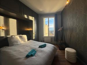 una camera da letto con un letto con due asciugamani verdi di Le petit Lyautey - Retro-chic atmosphere a Vichy