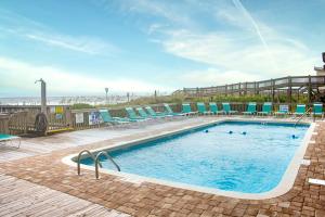 a swimming pool with chairs and the ocean in the background at Ocean Forest Colony in Myrtle Beach +3 photos