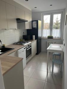 kuchnia z białymi szafkami, stołem i kuchenką w obiekcie Apartament Centrum w mieście Suwałki