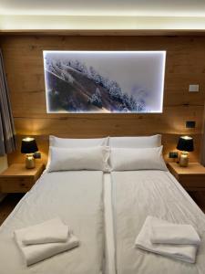 a bedroom with a white bed with two towels on it at Chalet Lilla Livigno in Livigno +41 photos