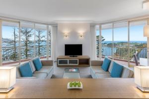 a living room with a television and large windows at Crowne Plaza Terrigal Pacific by IHG in Terrigal