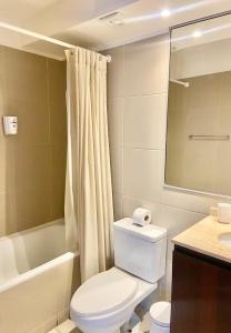 a bathroom with a toilet and a tub and a sink at Apartamento Alma Capital in Iquique