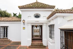 a white house with a door with a tiled roof at La Pinta Golf Villa Sotogrande in Sotogrande