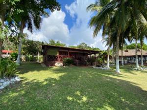 a house with palm trees in front of a yard at Coras Place Bacalar Lagoon front in Bacalar
