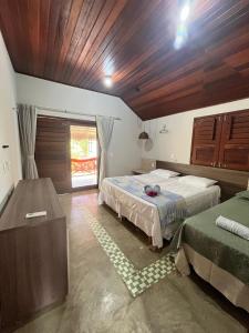 Un dormitorio con dos camas y techo de madera. en Bangalôs da Barra Chalé 2, en Barra Grande