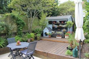 a patio with a table and chairs in a garden at Coastland Retreat in Bexhill