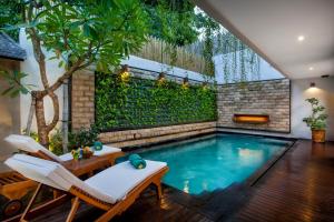 an indoor pool with two chairs and a table at Astagina Resort Villa and Spa in Legian