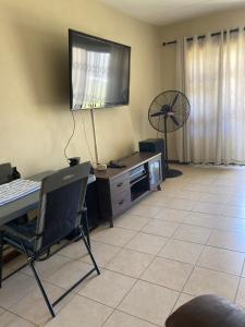 a living room with a desk with a television and a fan at SEASCAPE MEWS 27 in Cape Town