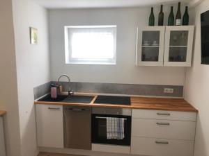 a kitchen with white cabinets and a sink and a window at Ferienwohnung Sommerblüte in Schweich