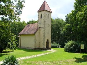 a small church with a tower on a grass field at Anna Lak in Magyarszombatfa